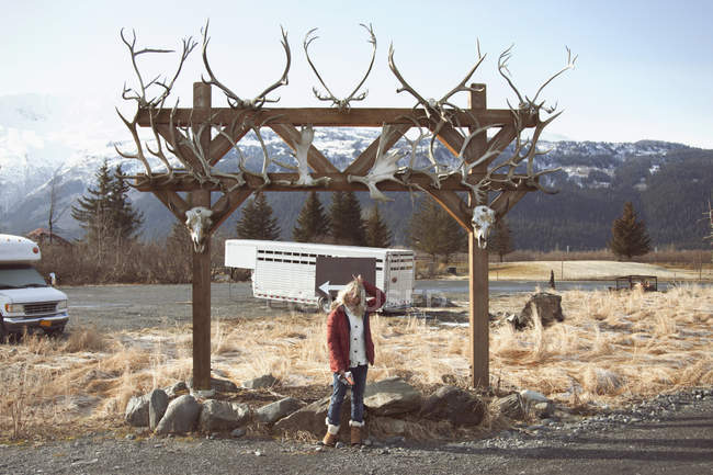Mujer por arco con cráneos de animales, Girdwood, Anchorage, Alaska - foto de stock