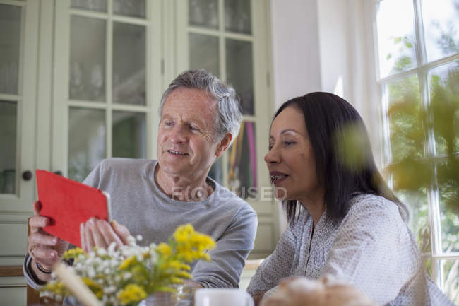 Coppia anziana, seduta a tavola, guardando il tablet digitale — Foto stock