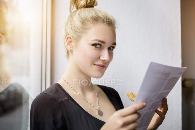Молода жінка читає документи на віконному сидінні — стокове фото