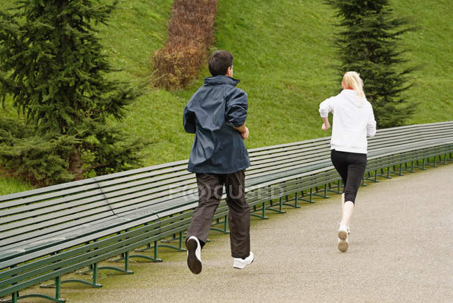 Uomo e donna che corrono lungo il sentiero, vista posteriore — Foto stock