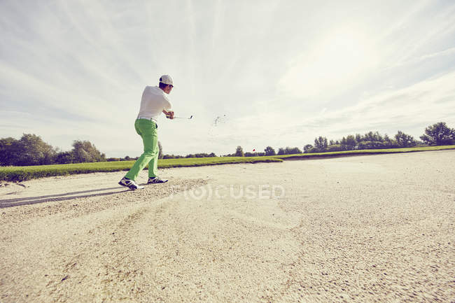 Golfista golpeando la pelota en la trampa de arena, Korschenbroich, Dusseldorf, Alemania - foto de stock