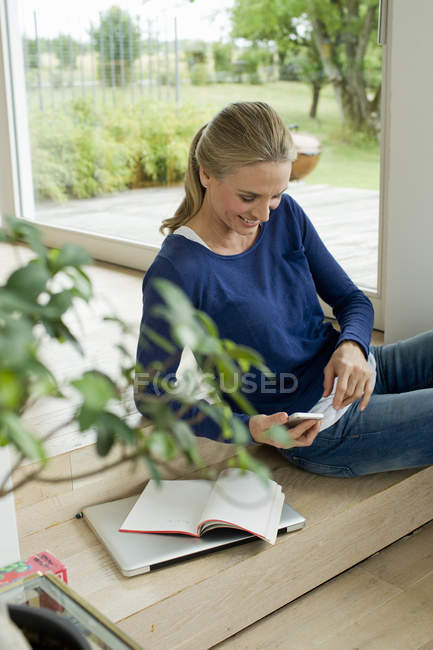 Mature woman using cell phone at home — Stock Photo