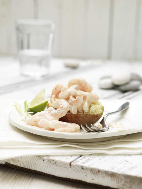 Prawn cocktail jacket potato with slice of lime and spring onion garnish — Stock Photo