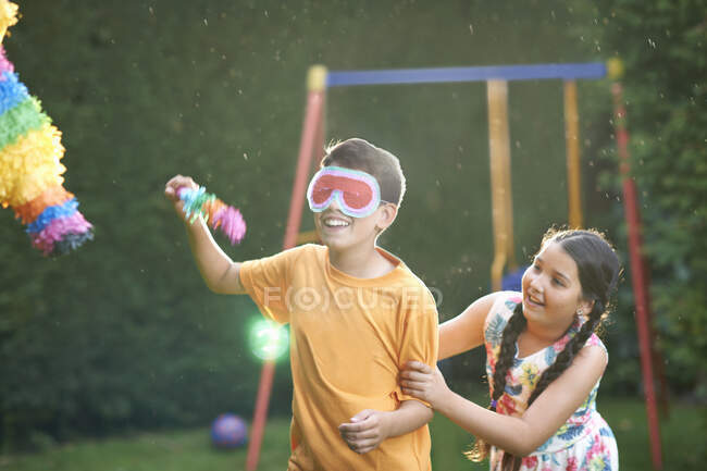Niños jugando piñata en el jardín - foto de stock