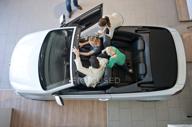 Vue aérienne de la famille essayant voiture convertible dans le concessionnaire automobile — Photo de stock