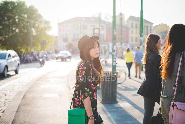 Молодая женщина, прогуливающаяся позади друзей в городе — стоковое фото