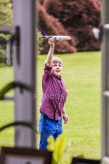 Хлопчик грає в саду з іграшковим літаком — стокове фото