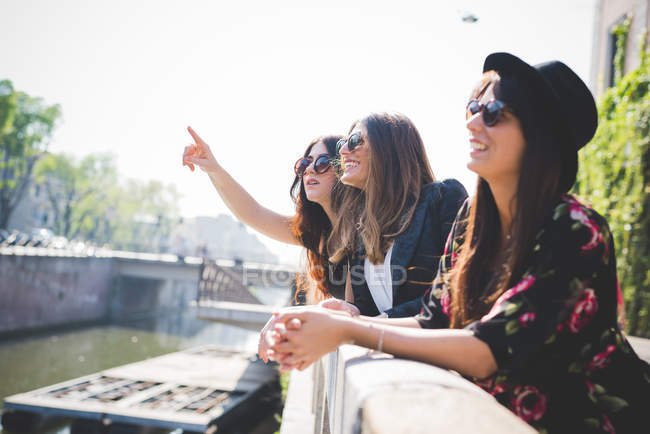 Drei stilvolle Frauen, die vom Flussufer der Stadt aufschauen — Stockfoto
