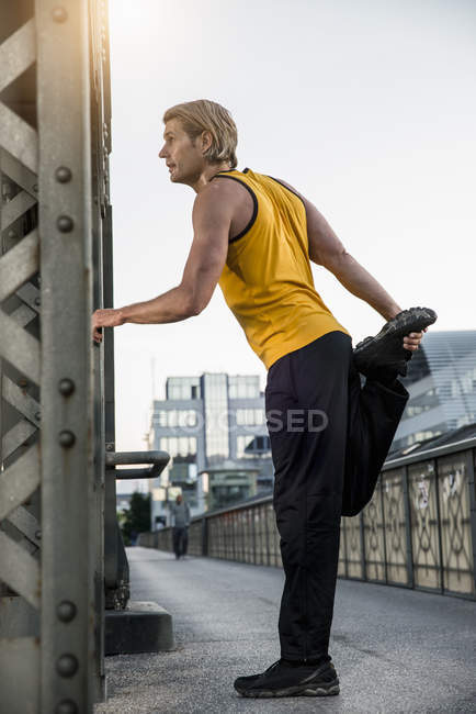 Man stretching legs on bridge, Monaco di Baviera, Baviera, Germania — Foto stock