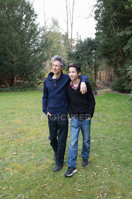 Homme mûr et fils adolescent marchant dans le jardin — Photo de stock