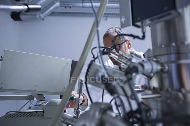Асистент лабораторії мікроскопії, що працює над обладнанням — стокове фото