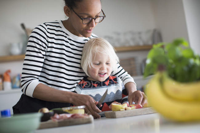 Madre che aiuta il figlio a preparare il cibo in cucina a casa — Foto stock