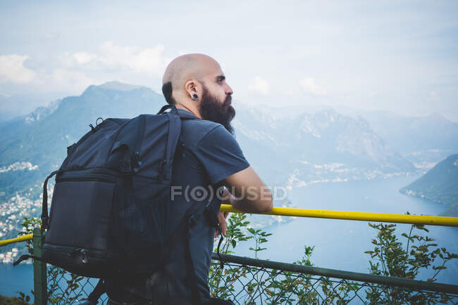 Hombre adulto en el balcón con vistas al lago Lugano, Suiza - foto de stock