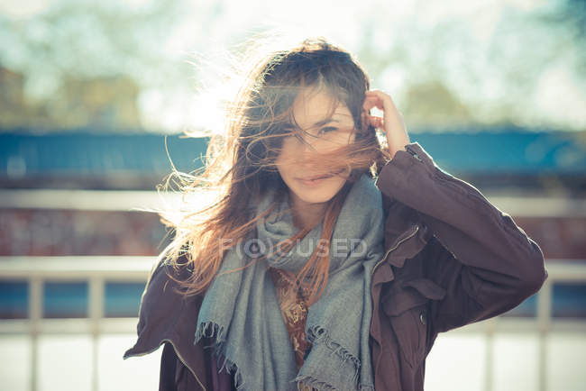 Mid adult woman standing on breezy roadside with hand in hair — Stock Photo
