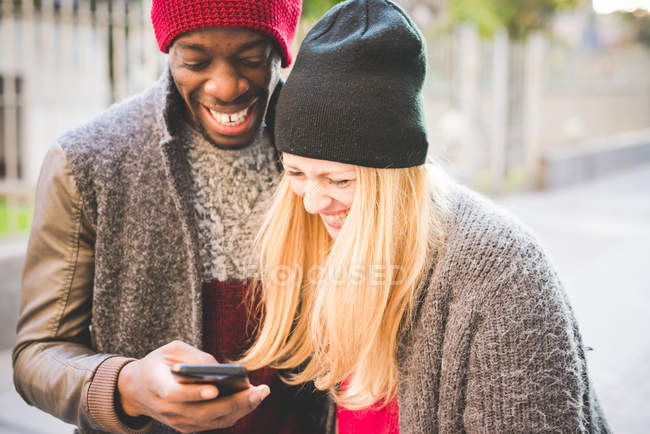 Casal sorrindo para a mensagem no smartphone — Fotografia de Stock