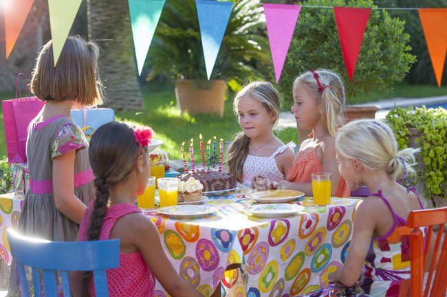 Девушка с друзьями за столом с праздничным тортом — стоковое фото