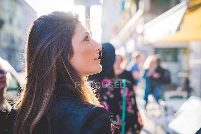 Молодая женщина смотрит вверх с городской улицы — стоковое фото
