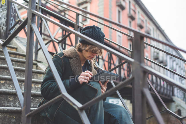 Человек с цифровой табличкой на ступеньках, Милан, Италия — стоковое фото
