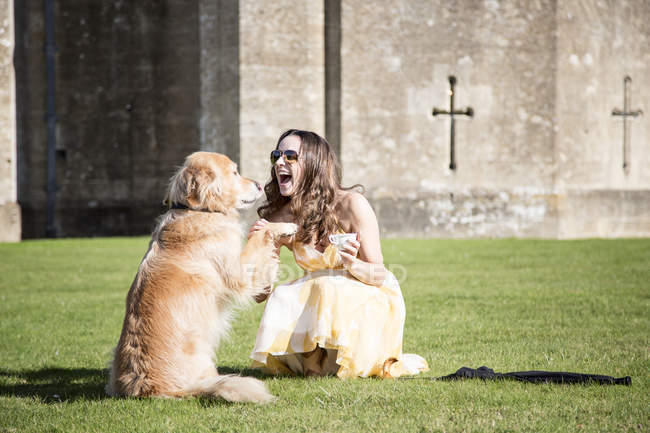 Woman posing with cup of tea and golden retriever dog at Thornbury Castle, South Gloucestershire, UK — Stock Photo