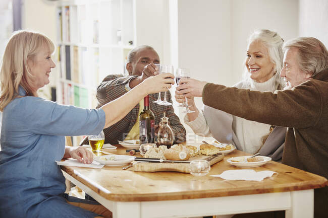 Старші друзі роблять тост за обіднім столом. — стокове фото