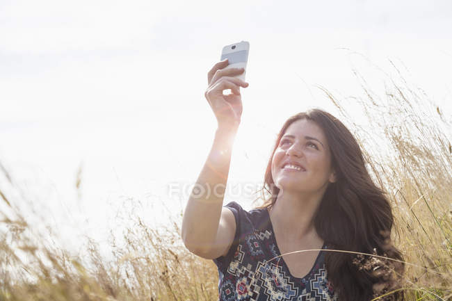 Giovane donna scattare selfie con smartphone in campo — Foto stock