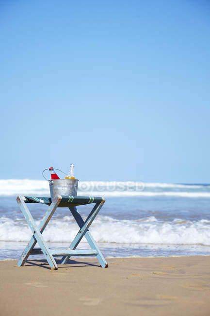 Bouteilles de jus en verre dans un seau à glace sur un transat sur la plage — Photo de stock