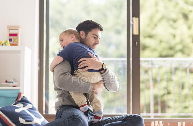 Padre che abbraccia giovane figlio, in casa — Foto stock