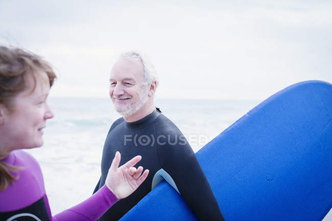 Отец и дочь с доской для серфинга на пляже — стоковое фото