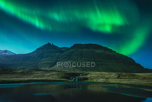 Aurora Boreal en el cielo por encima de la colina y todavía lago - foto de stock