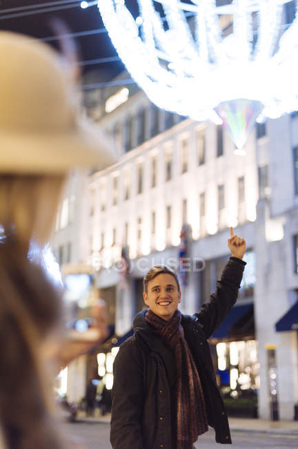 Молодая пара, указывающая на рождественские огни на улице Нью-Бонд, Лондон, Великобритания — стоковое фото