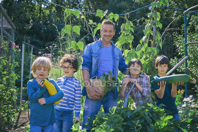 Man and sons holding vegetables on allotment — Stock Photo