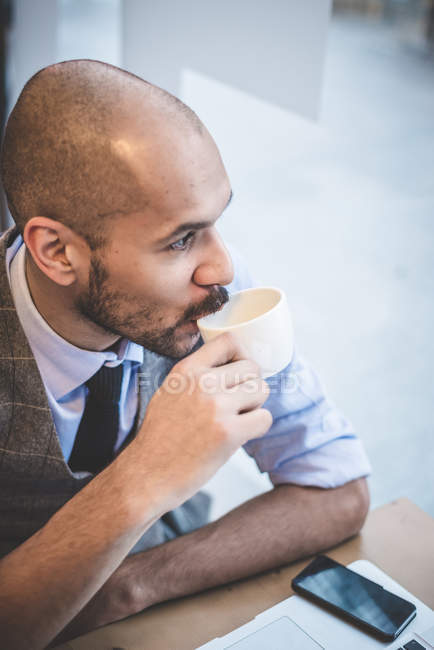 Vista de ángulo alto del hombre de negocios sentado en la cafetería bebiendo café - foto de stock