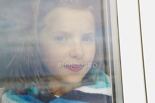 Portrait of girl wrapped in towel gazing from holiday apartment window — Stock Photo