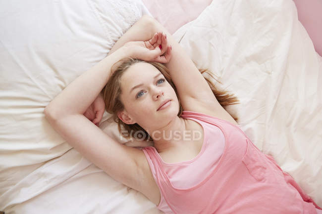 Girl lying on bed gazing upwards — Stock Photo
