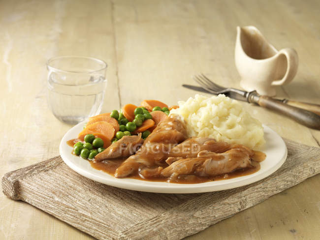 Plate of chicken breast in gravy with peas, carrots and mashed potatoes — Stock Photo