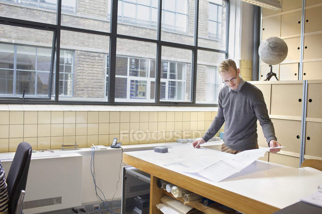 Diseñador masculino mirando el plano en la oficina creativa - foto de stock