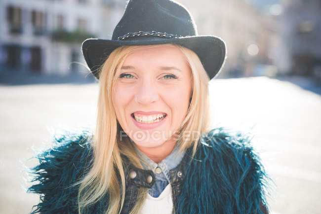 Portrait of young woman wearing furry jacket in town square — Stock Photo