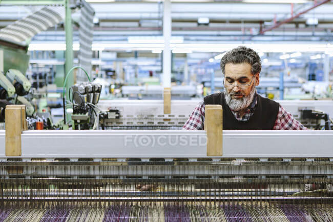 Male factory worker on weaving machine in woollen mill — Stock Photo