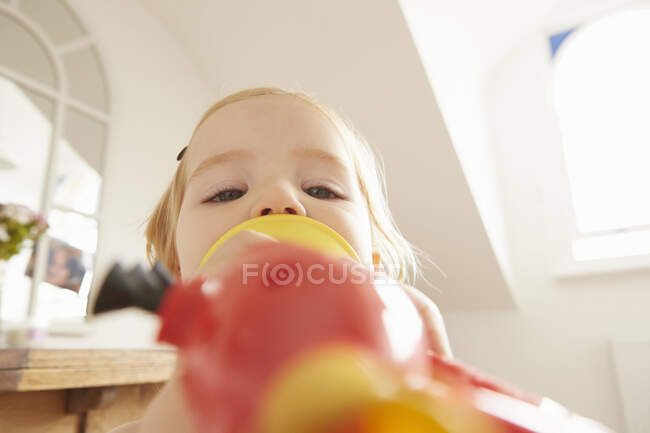 Close up de criança feminina tocando trompete de brinquedo — Fotografia de Stock