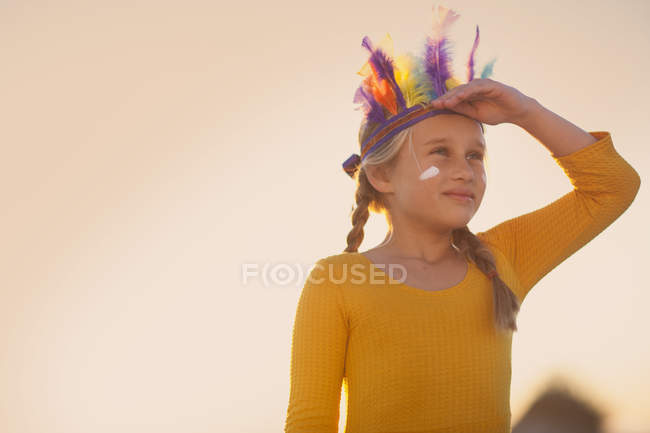 Girl dressed as native american in feather headdress with hand shading eyes — Stock Photo