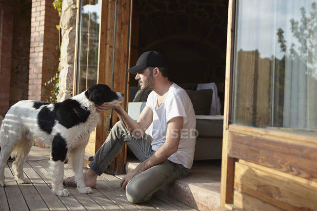 Mitte erwachsener Mann streichelt Hund auf Terrasse — Stockfoto