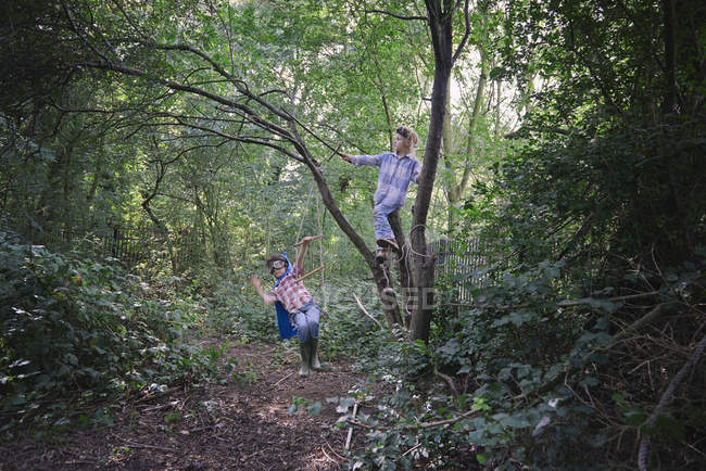 Niños vestidos con capa jugando en el bosque - foto de stock