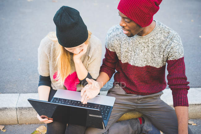 Couple using laptop on pavement — Stock Photo