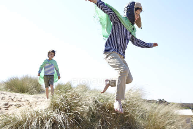 Two young boys, wearing fancy dress, playing on beach — Stock Photo