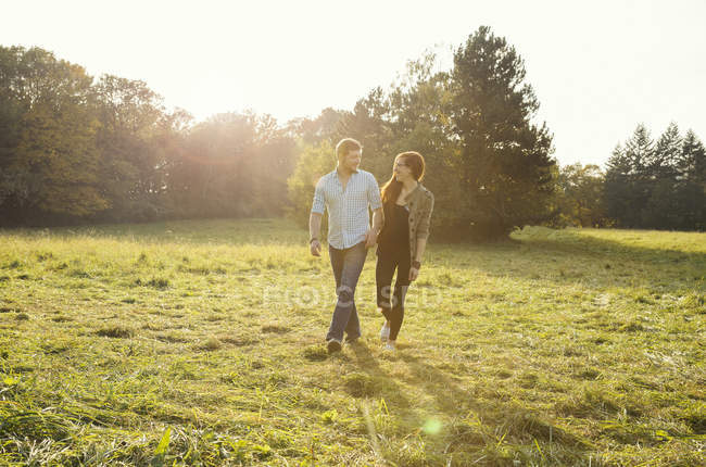 Young couple walking hand in hand in park — Stock Photo