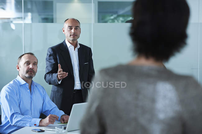 Hommes et femmes d'affaires débattant à travers la table de conférence — Photo de stock