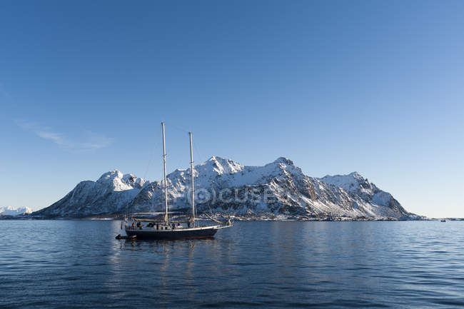 Barco que navega frente a montañas nevadas - foto de stock