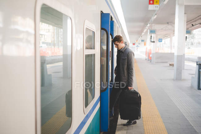 Jungunternehmer steigt mit Koffer in Zug ein. — Stockfoto