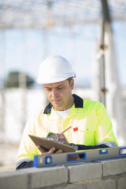 Site manager checking spirit level on construction site wall — Stock Photo