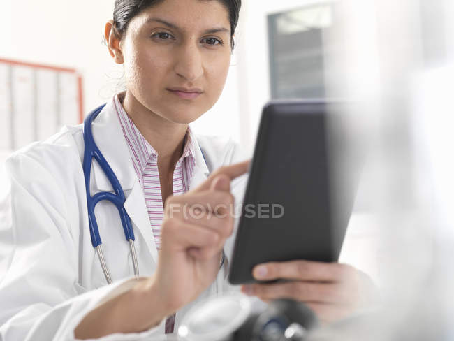 Женщина-врач, использующая цифровой планшетный сенсорный экран для медицинских записей — стоковое фото